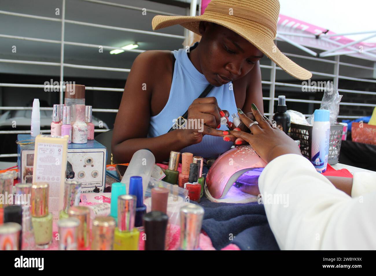 Francistown, Botsuana. Januar 2024. Eine Frau trägt nagellack auf einen Kunden in einer Straße in Francistown, Botswana, am 11. Januar 2024 auf. Immer mehr junge Batswana-Frauen nutzen eine Lawine von Geschäftsmöglichkeiten in der Beauty- und Modebranche, die durch importierte chinesische Produkte bereitgestellt werden. ZU „Feature: Batswana Frauen finden Geschäftsmöglichkeiten in chinesischen Produkten“ Credit: Shingirai Madondo/Xinhua/Alamy Live News Stockfoto