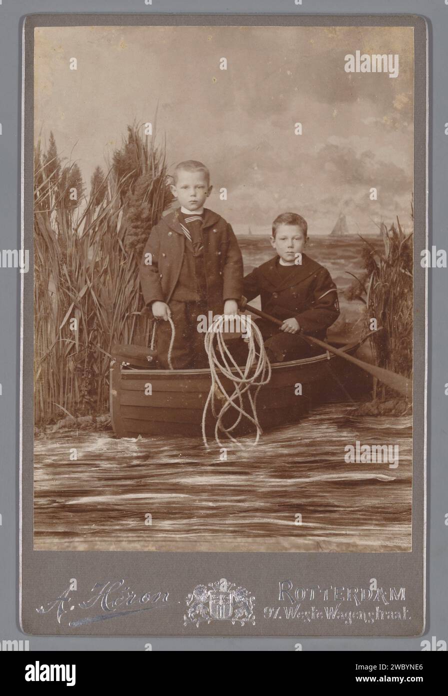 Porträt zweier unbekannter Knaben in einem Ruderboot, Adolf Héron, um 1894 - um 1930 Fotografie. Foto des Kabinetts Rotterdam, fotografische Unterstützung. Studiobedarf aus Pappe  Fotograf. Ruderboot, Kanu usw. Stockfoto
