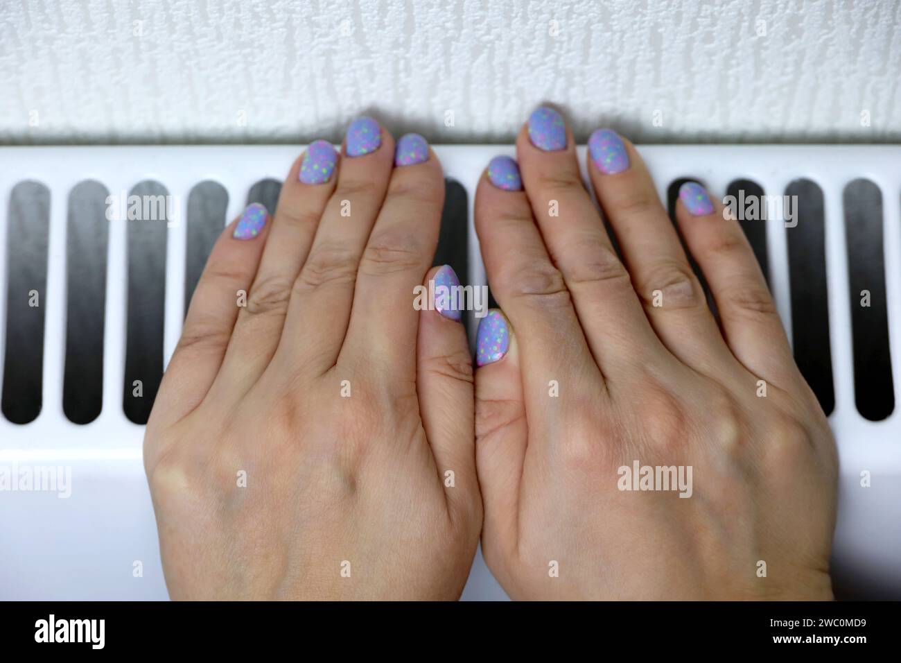 Heizkörper mit weiblicher Handbedienung. Winter kaltes Wetter, Heizsaison zu Hause Stockfoto