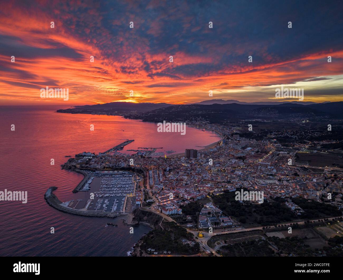 Sonnenuntergang mit rotem Himmel über der Bucht und der Stadt Palamós. Luftaufnahme (Costa Brava, Baix Empordà, Girona, Katalonien, Spanien) Stockfoto