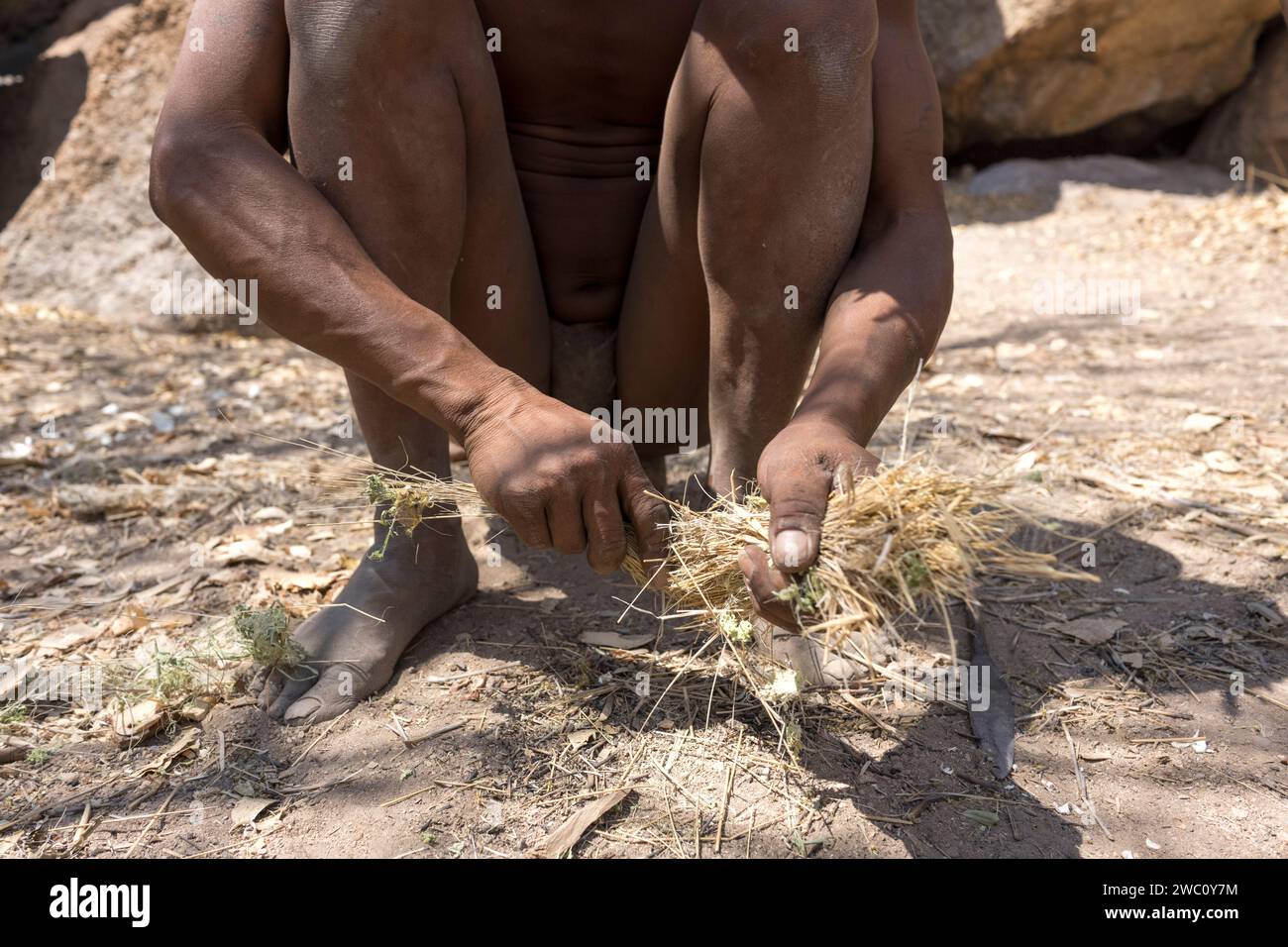 Ein ortsansässiger San Buschmann bereitet sich auf traditionelle Weise darauf vor, Feuer in Namibia zu machen Stockfoto