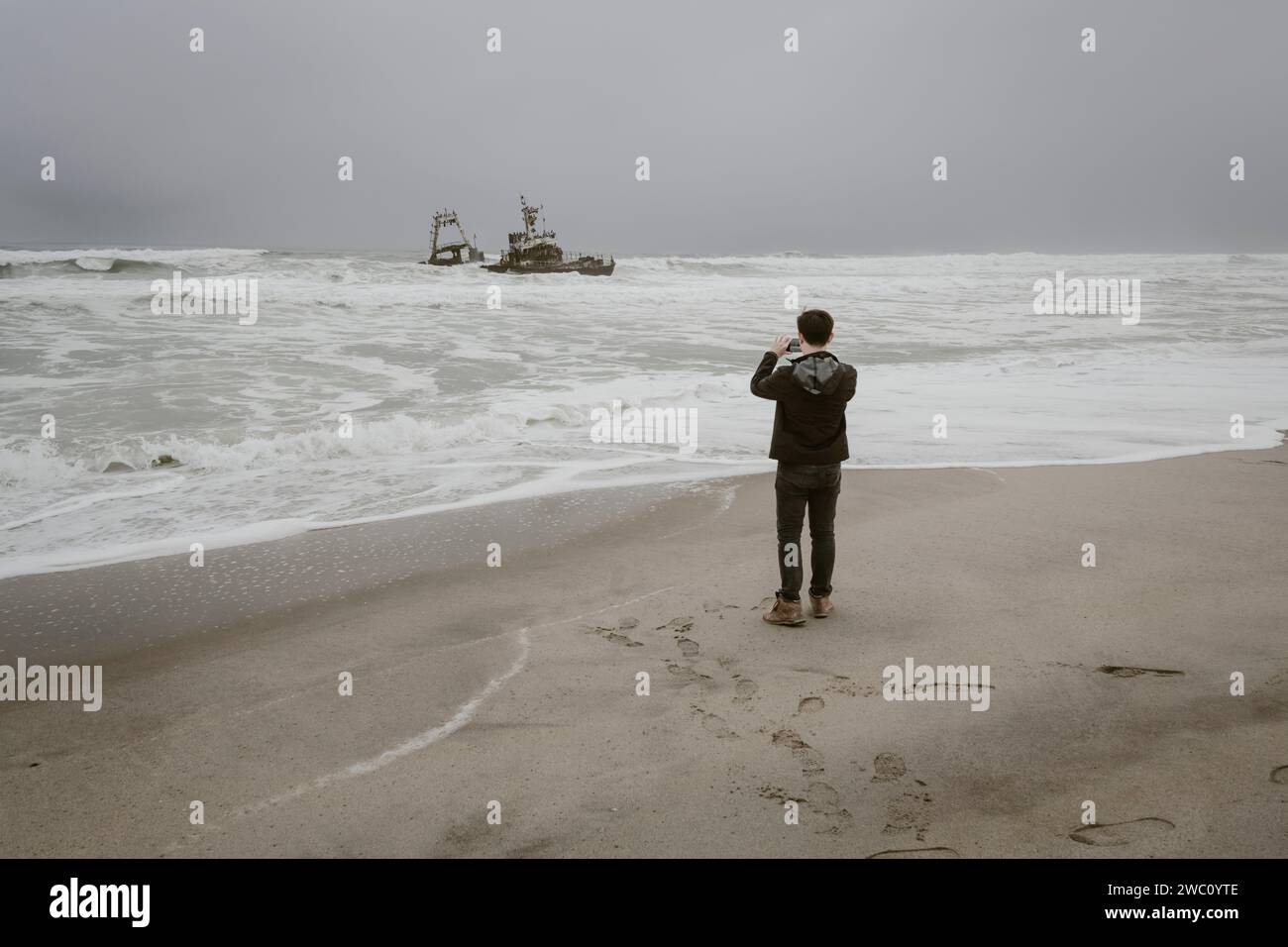 Ein Tourist fotografiert eines der Schiffswracks an der Skeleton Coast in Namibia Stockfoto