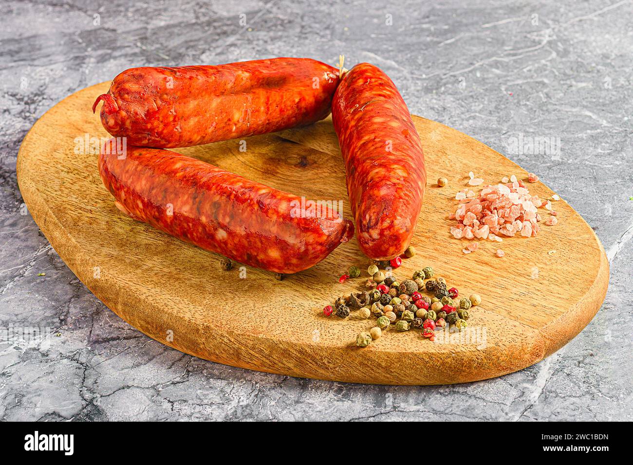 Eine Nahaufnahme von Würstchen und Gewürzen auf einem hölzernen Schneidebrett Stockfoto