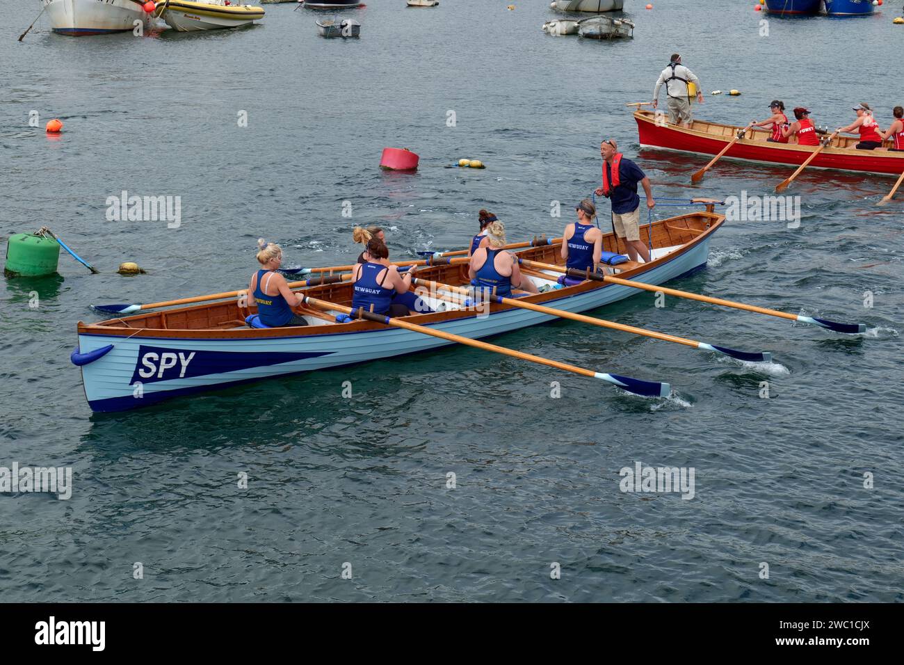 Eine Besatzung von SPIONEN geht zum Start des Pilotenrennens der Damen bei der Regatta, Mevagissey, Cornwall, England, Großbritannien Stockfoto