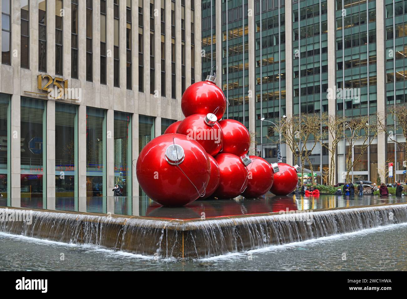 Weihnachten in New York City. Übergroße, rote Ornamente auf dem Brunnen. 1251 6th Avenue Building (Exxon Building) gegenüber von Radio City Mus Stockfoto