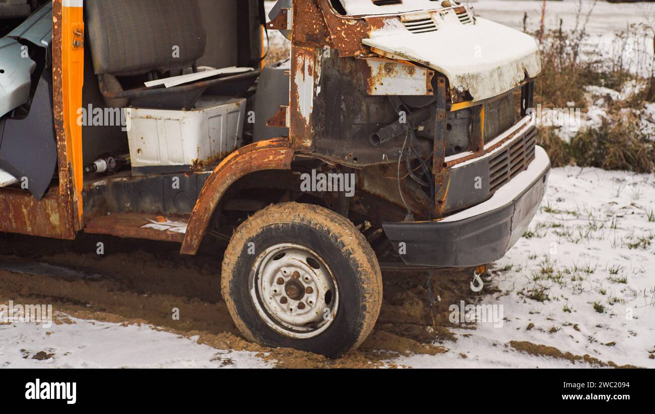 Im Winter kein geeignetes Auto. Ein alter orangener, rostiger Minibus auf einem schneebedeckten Hintergrund. Stockfoto