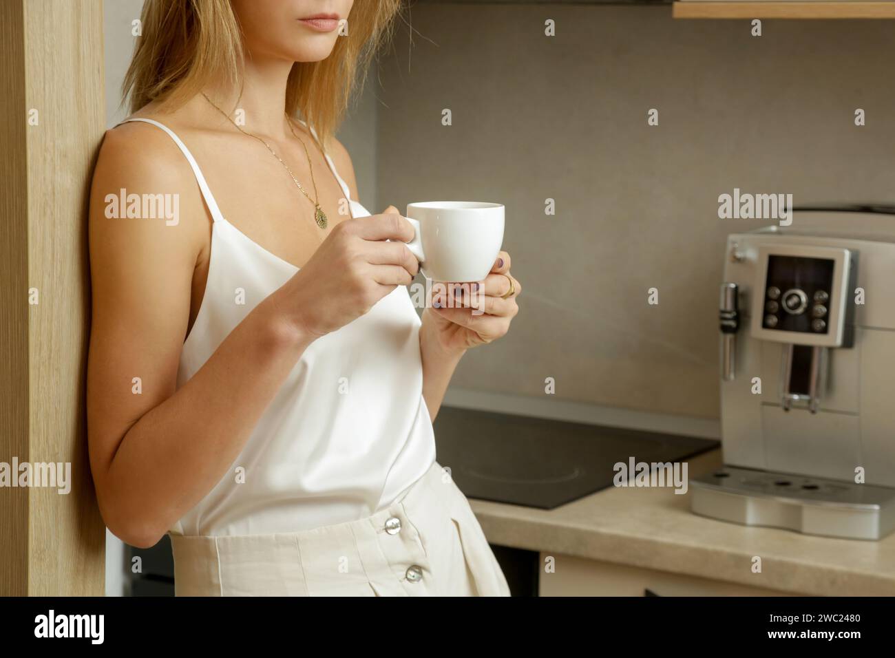 Schöne Frau, die ihren ersten Morgenkaffee in der Küche trinkt Stockfoto