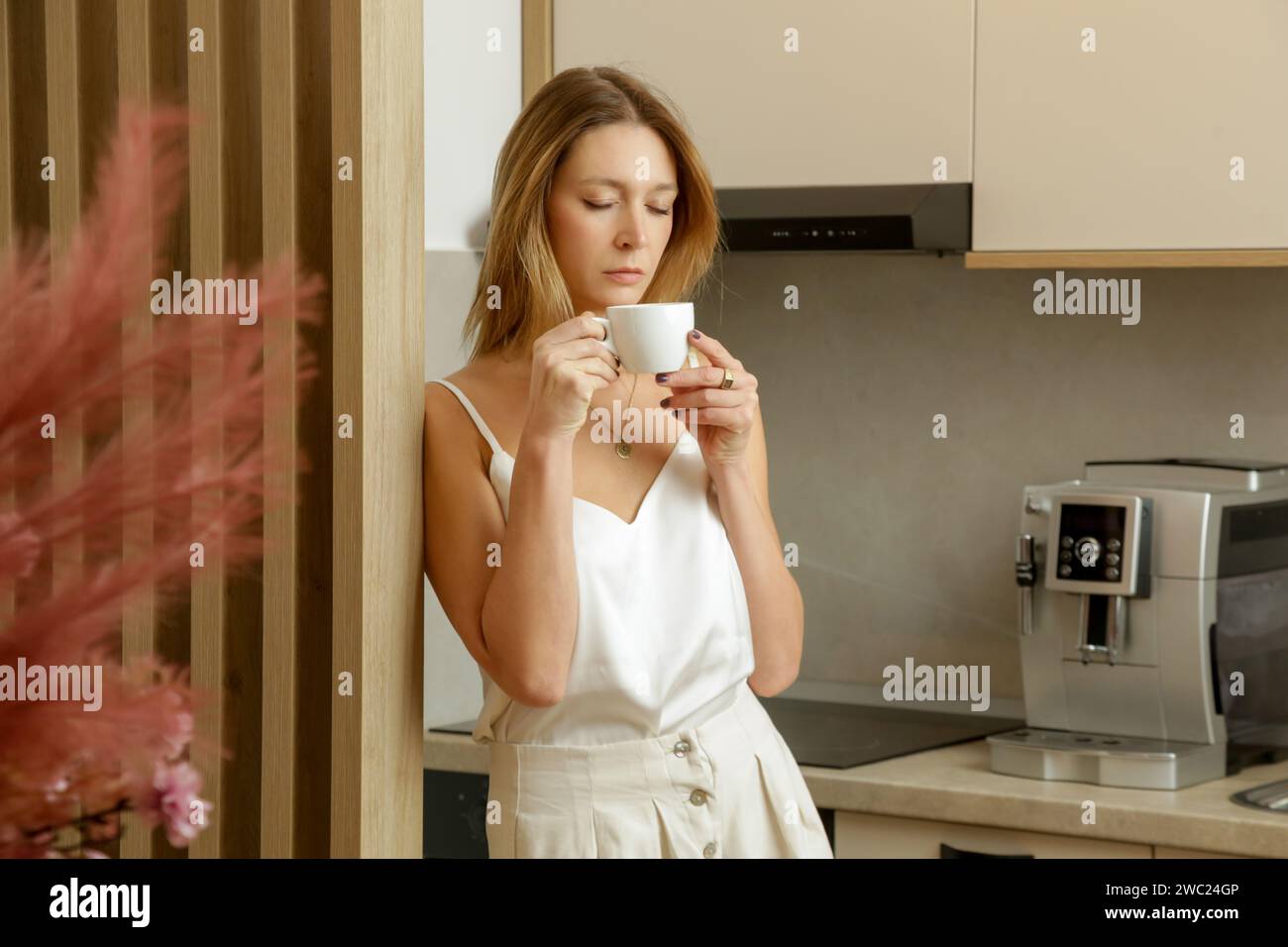 Schöne Frau, die ihren ersten Morgenkaffee in der Küche trinkt Stockfoto