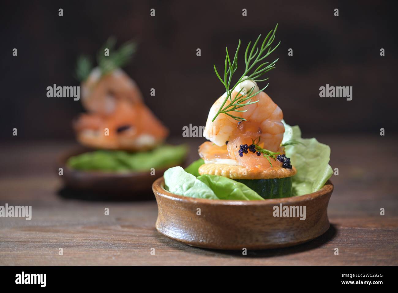 Party-Snack aus Garnelen, Lachs, Kaviar und Dill garnieren in kleinen Holzschalen auf einem dunklen rustikalen Tisch, Vorspeise für Feiertage wie Weihnachten, Thanksgi Stockfoto