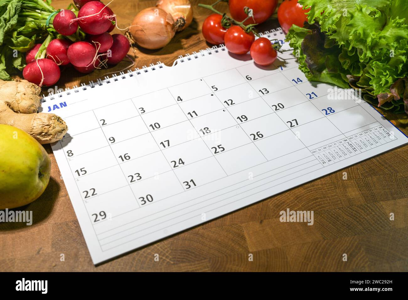 Kalender mit Monat Januar umgeben von frischem Gemüse und Obst auf einem Holztisch, Neujahrsziele, gesunde Lebensmittel zu essen und Gewicht zu verlieren, Kopie s Stockfoto
