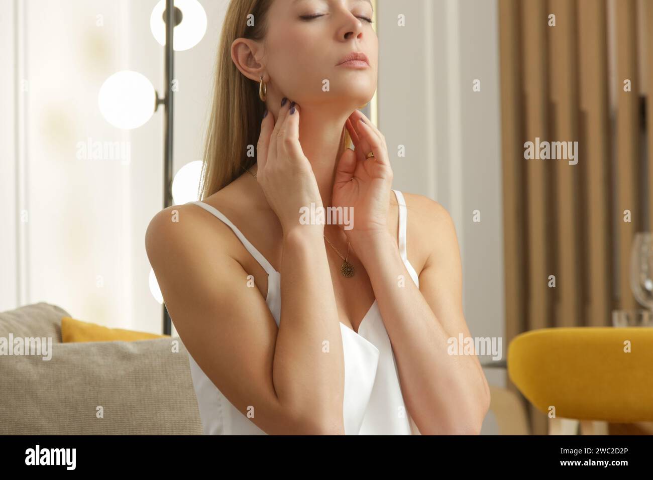 Eine kaukasische Frau, die ihren Hals berührt. Halsschmerzen, Erkältung, Grippe, Tonsillitis oder Schilddrüsenproblem Stockfoto