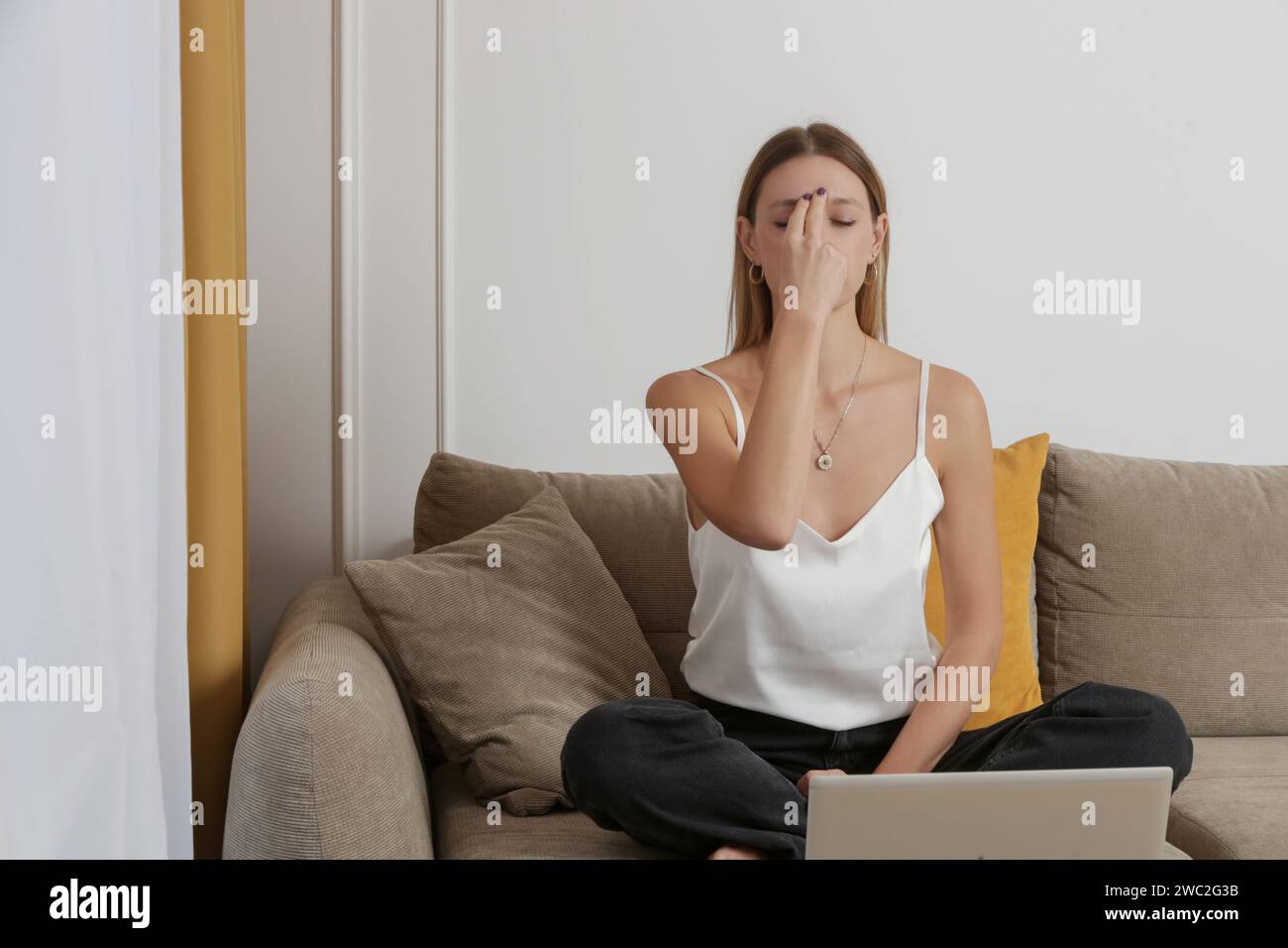 Frau übt Meditation und Atemübungen auf dem Sofa im Wohnzimmer, entspannter gemütlicher achtsamer Lebensstil Stockfoto