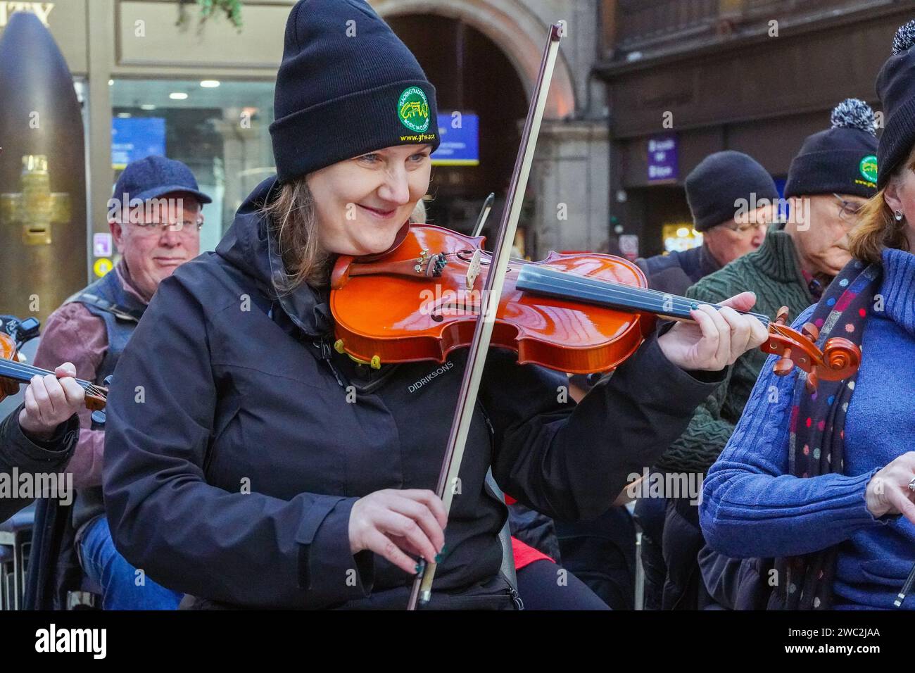 Glasgow, Großbritannien. Januar 2024. Schüler und Tutoren des Glasgow Fiddle Workshop, bekannt als „GFW“, einer schottischen Wohltätigkeitsorganisation, die 1992 als Geigen-Workshop begann, spielten für Reisende im Central Railway Station in Glasgow, Schottland. Der Workshop unterstützt und fördert die Teilnahme an traditioneller Musik und bietet Unterricht in verschiedenen Instrumenten wie Akkordeon, Geige, Banjo und Mandoline. Quelle: Findlay/Alamy Live News Stockfoto