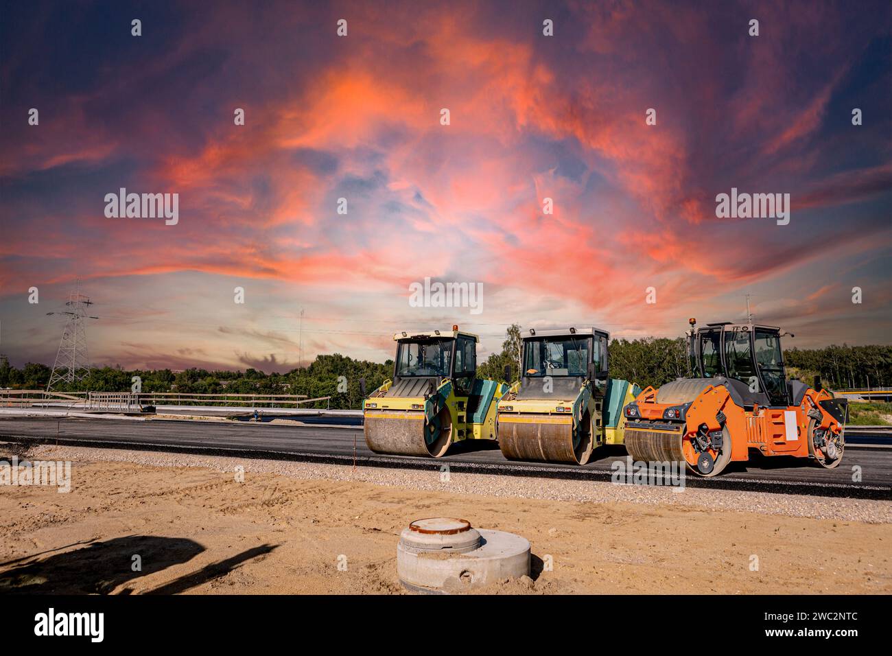 Autobahnbau. Asphalt gießen, Schallschutz installieren. Schwere Baumaschinen auf der Baustelle, Walze, Bagger, Planierraupe Stockfoto