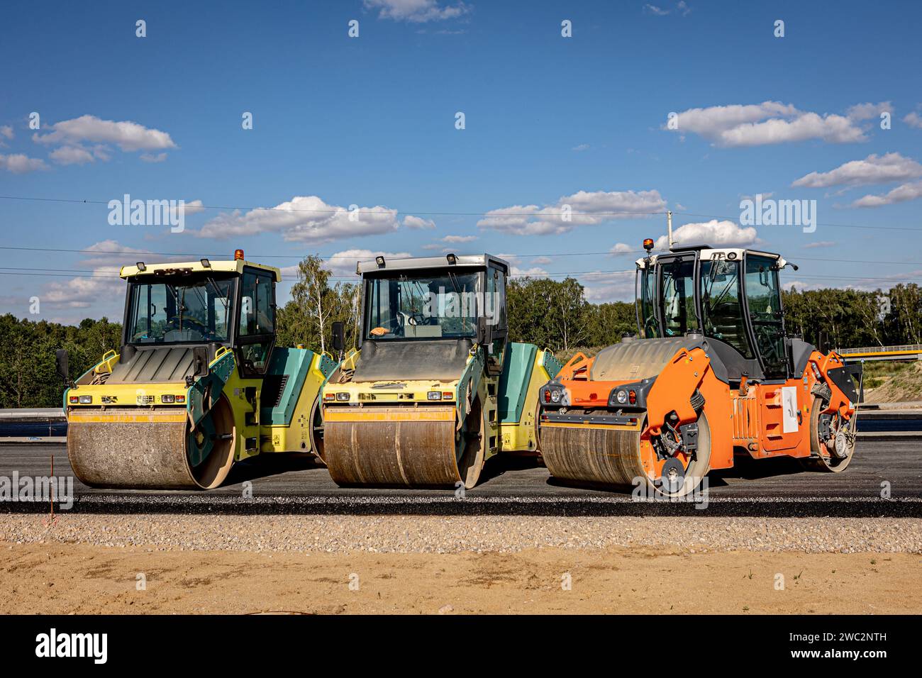 Autobahnbau. Asphaltgießen und Einbau von Schallschutzvorrichtungen. Schwere Baumaschinen auf der Baustelle, Walze, Bagger, Bulldoz Stockfoto