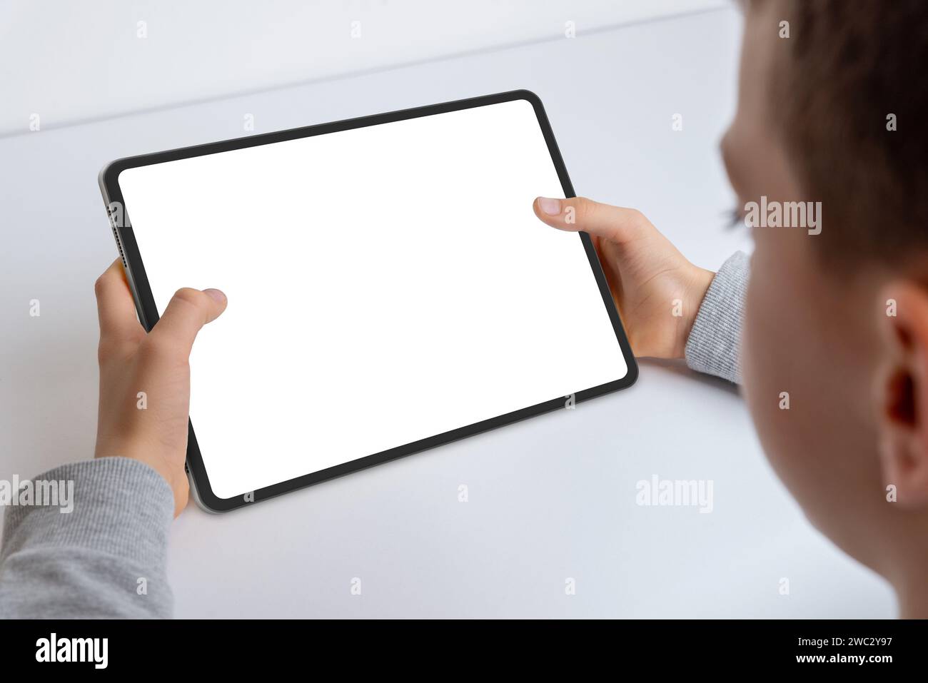 Nahaufnahme der Hände eines Jungen, der ein Tablet-Modell hält. Arbeiten, indem ein isolierter weißer Bildschirm für die App-Präsentation präsentiert wird. Moderne Technik bei Kindern Stockfoto