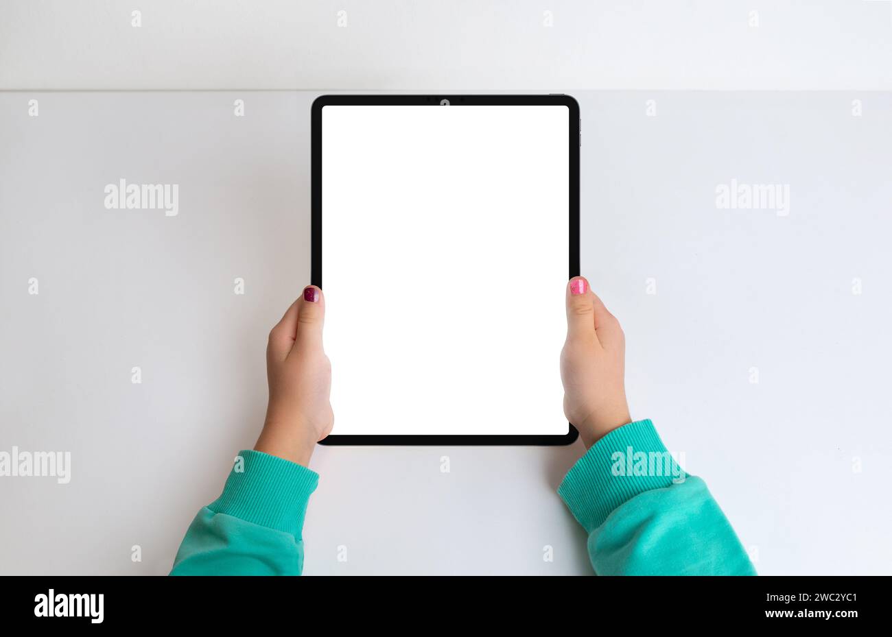 Mädchenhände mit Tablet in einer flachen Draufsicht, mit isoliertem Bildschirm für Mockup. Schaffen Sie eine moderne Ästhetik für digitale Inhalte und App Presen Stockfoto
