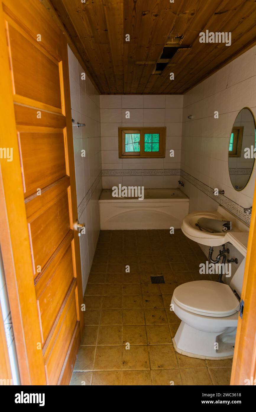 Bad mit Holzdecke, Badewanne, Waschbecken, Kommode und rundem Spiegel in einem verlassenen Haus Stockfoto Bad mit Holzdecke, Badewanne, Waschbecken, Kommode und rundem Spiegel in einem verlassenen Haus Stockfoto