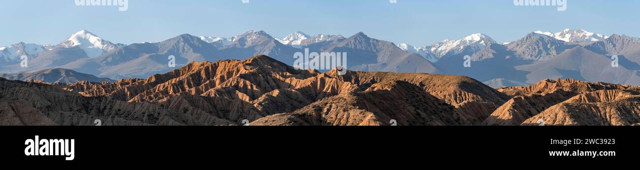 Sonnenaufgang über Canyons, Tian Shan Berge im Hintergrund, erodierte hügelige Landschaft, Badlands, Tal der vergessenen Flüsse, in der Nähe von Bokonbayevo Stockfoto