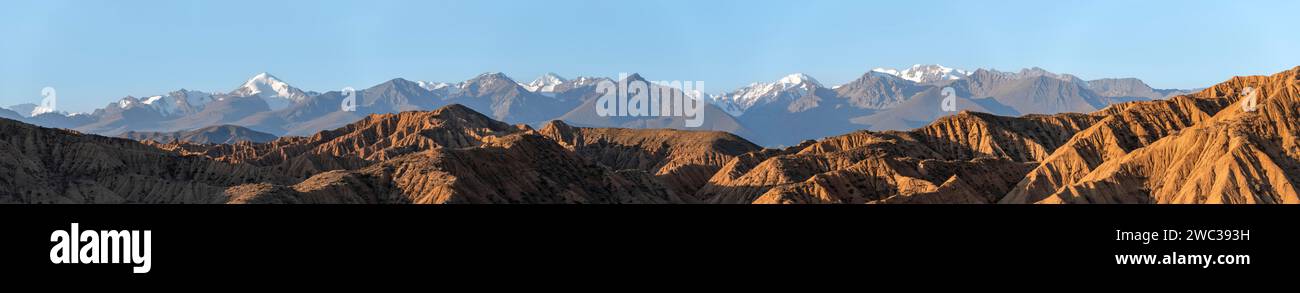 Sonnenaufgang über Canyons, Tian Shan Berge im Hintergrund, erodierte hügelige Landschaft, Badlands, Tal der vergessenen Flüsse, in der Nähe von Bokonbayevo Stockfoto