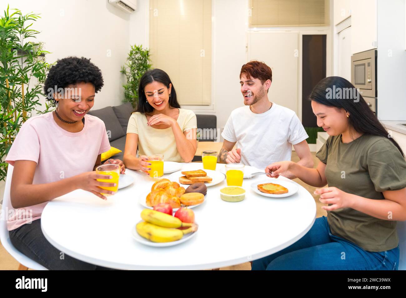 Glückliche Freunde, die zusammen ein gesundes Frühstück essen, sitzen an einem Tisch in der Wohnung Stockfoto