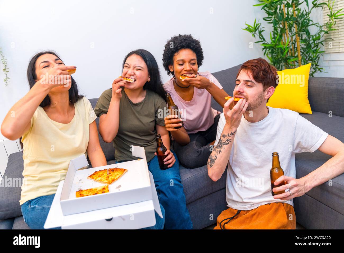 Ausgehungerte Freunde essen eine leckere Pizza und trinken Bier zu Hause Stockfoto