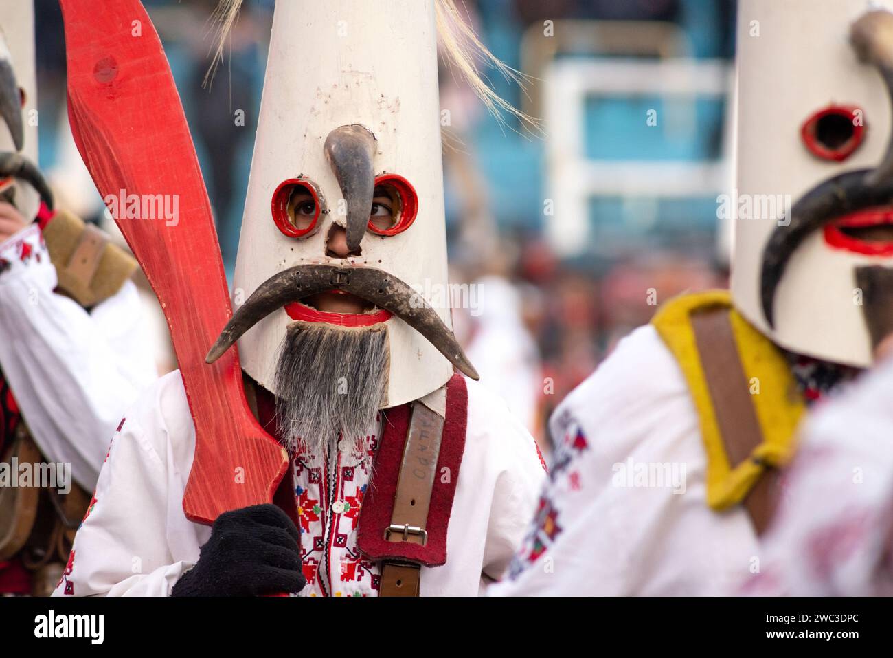 Kukeri-Tänzer aus Zentralbulgaren mit komplexen Kostümen und unverwechselbaren hohen konischen Masken beim jährlichen Simitlia Winter Festival in Simitli, Blagoevgrad County, Bulgarien Stockfoto