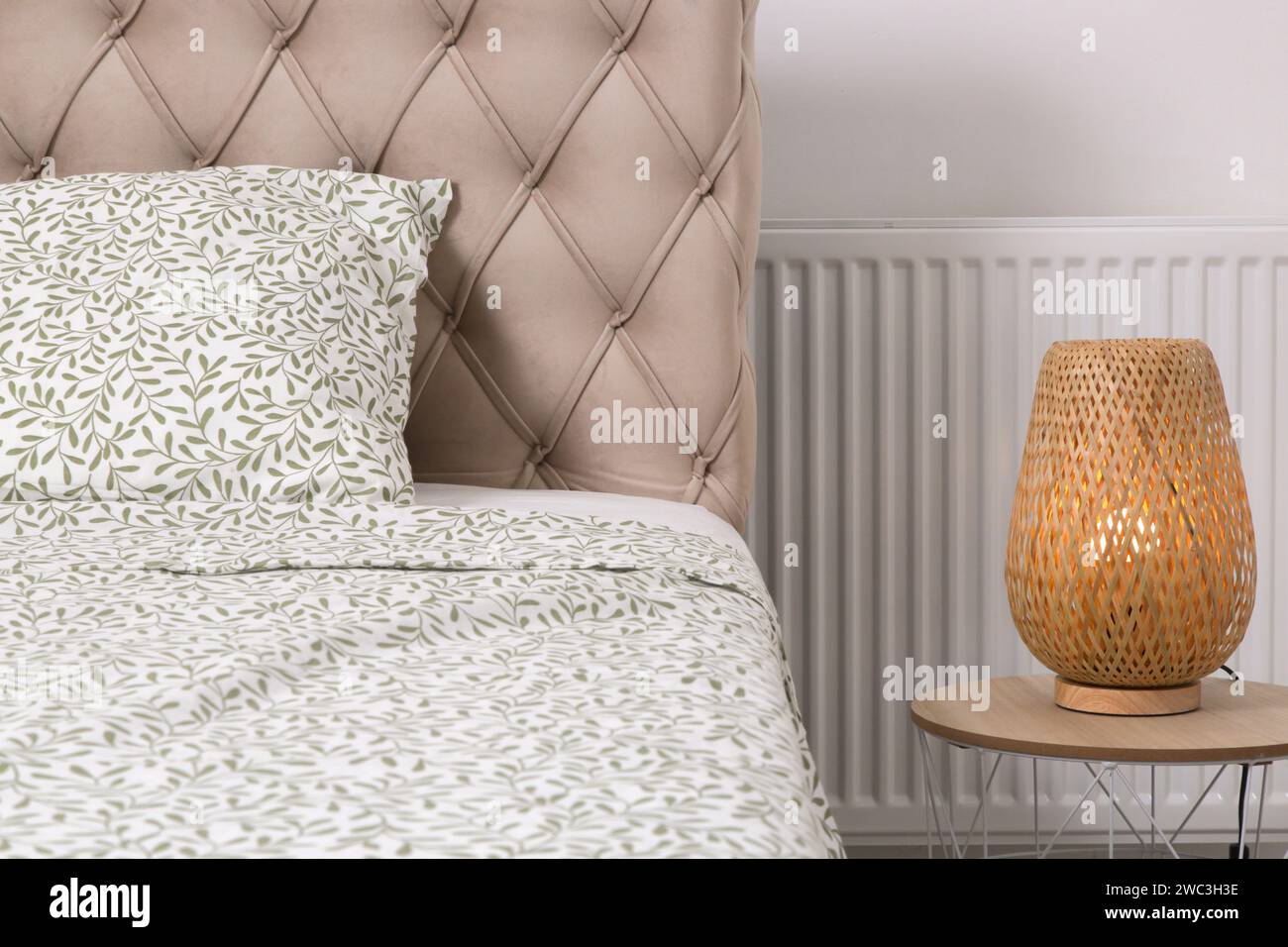 Beigefarbenes französisches Samtbett mit Nachttisch und Lampe an der Seite, gemütliches und einfaches Schlafzimmer Stockfoto