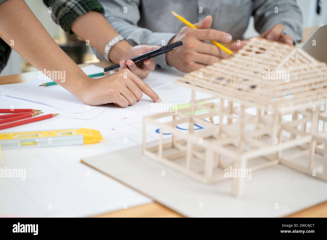 Asiatischer Designer, der sich ein Modell eines Hauses ansieht. Stockfoto