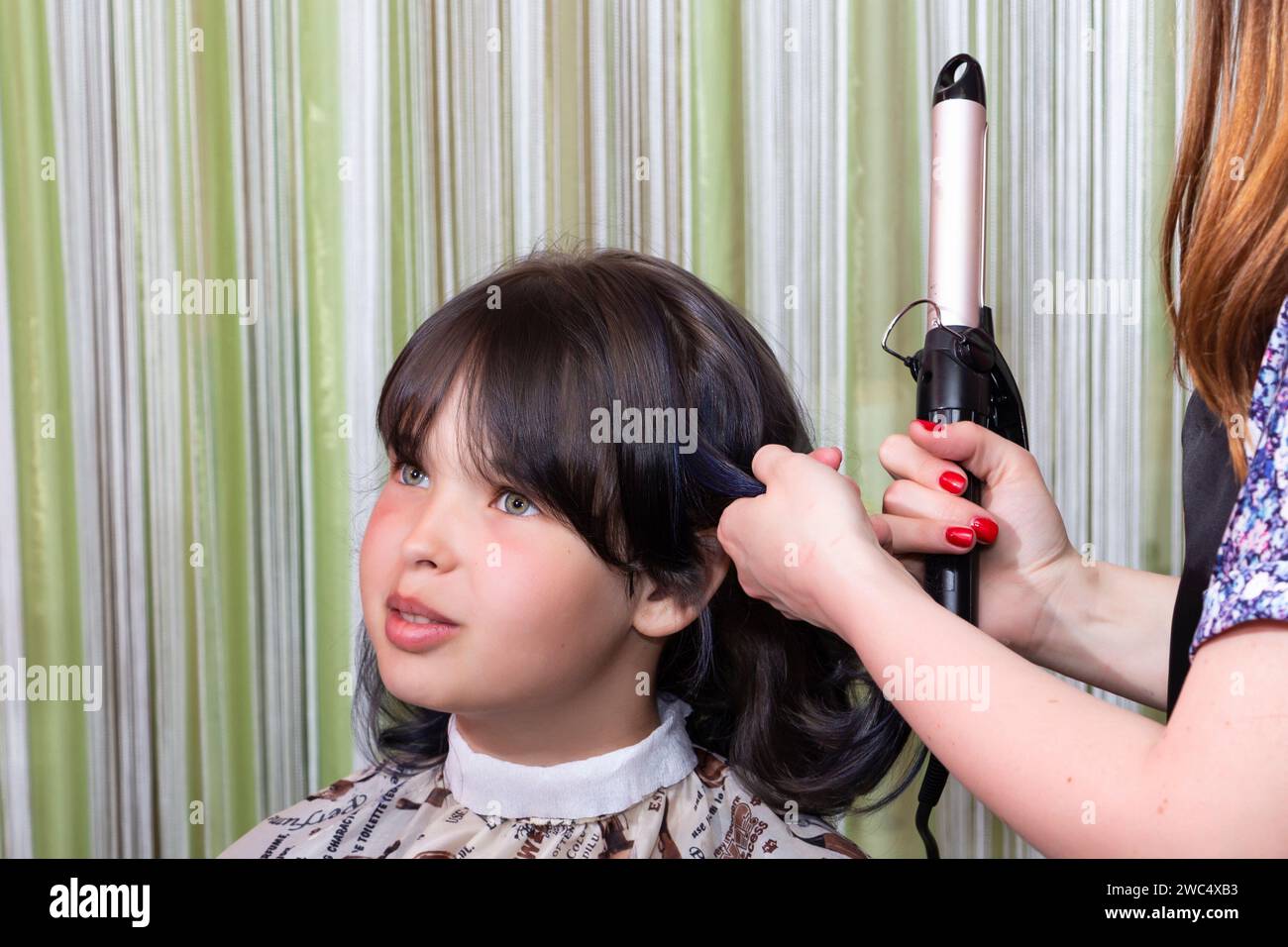Ein Mädchen im Teenageralter in einem Schönheitssalon macht sich die Haare und bereitet sich auf die Feier vor. Stockfoto