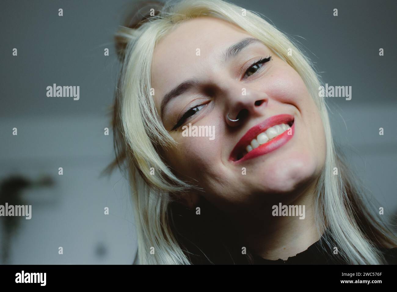 Eine freudige Frau mit einem entzückenden Gesichtsausdruck hält einen köstlichen Donut im Mund und zeigt ihre Zufriedenheit und Zufriedenheit Stockfoto