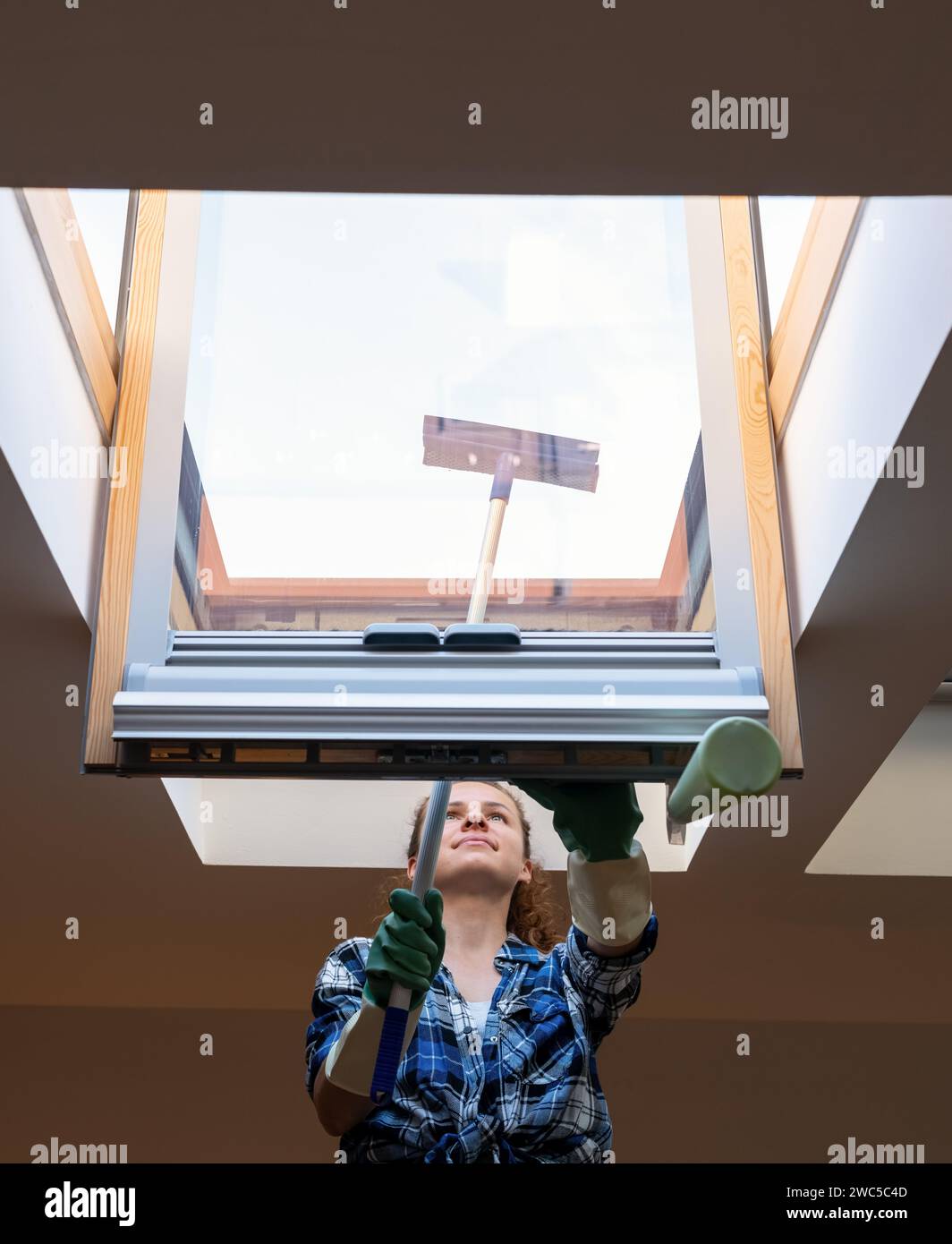 Frau, die zu Hause das Dachfenster wäscht. Hausarbeit machen. Stockfoto