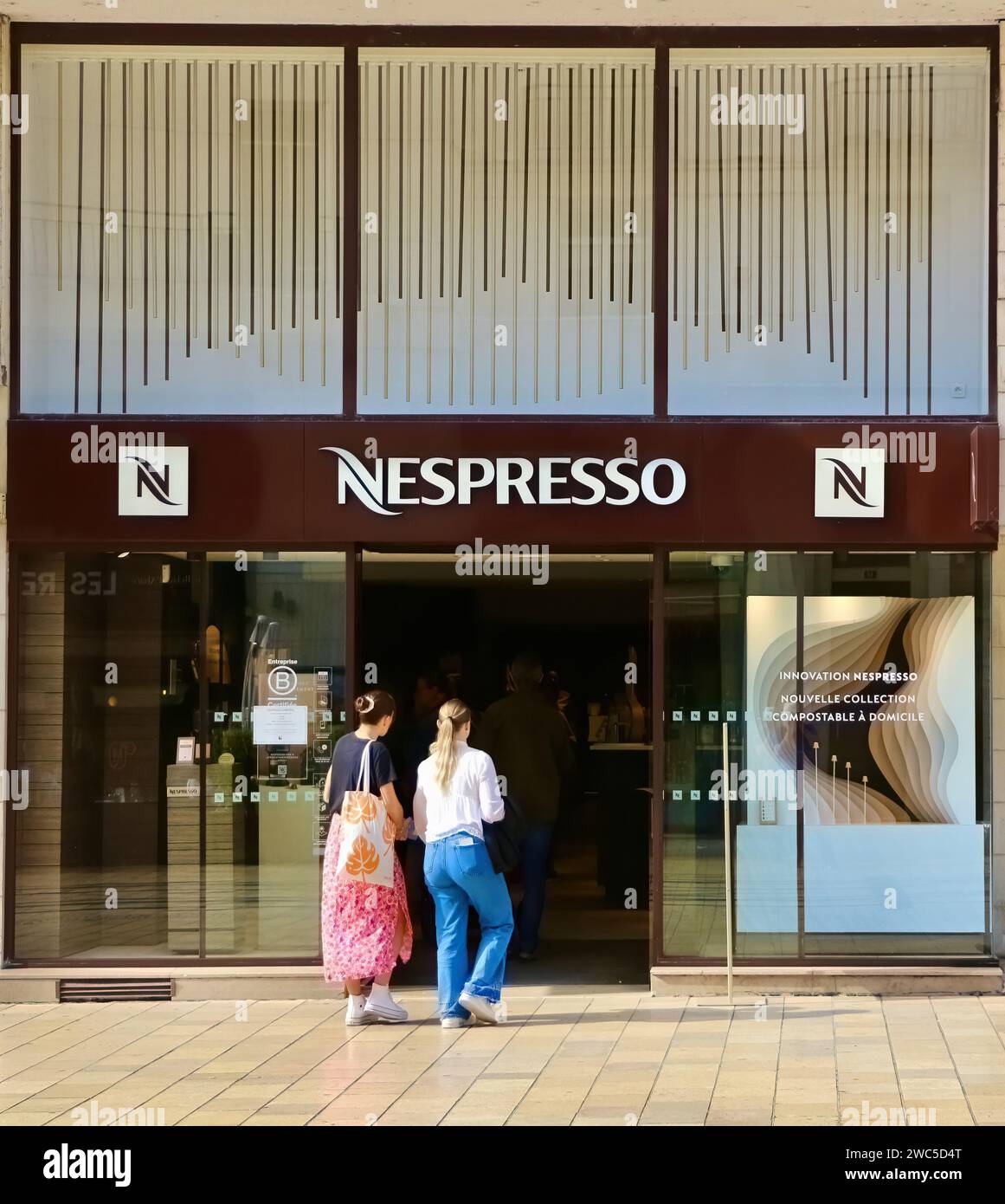 Nespresso-Kaffeemaschinen und Eingang zum Kaffeekapselladen mit zwei Personen, die an einem sonnigen Tag in die Rue nationale Tours Indre-et-Loire Frankreich gehen Stockfoto