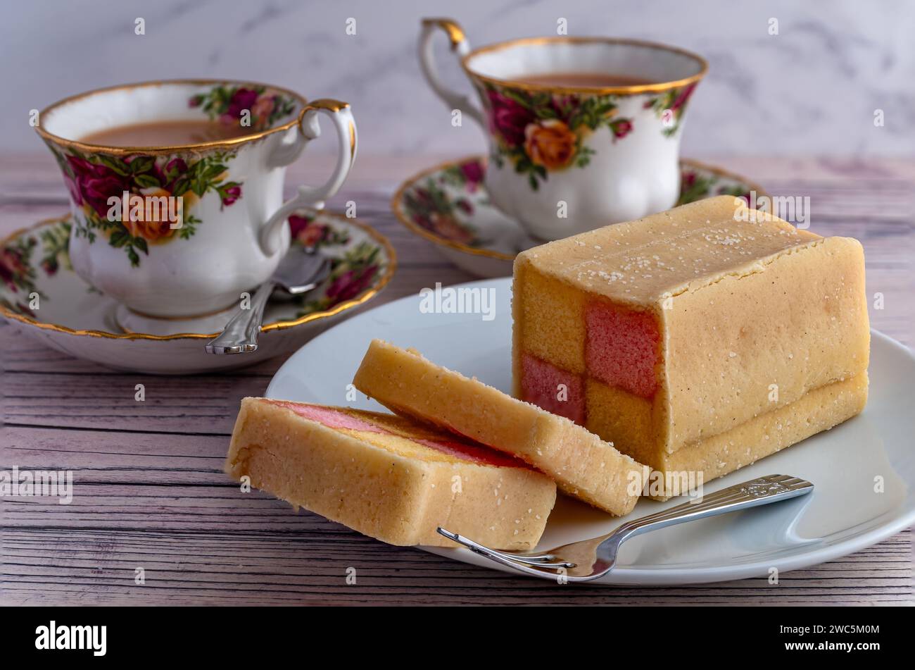 Battenberg-Kuchen und Porzellantassen mit Tee Stockfoto