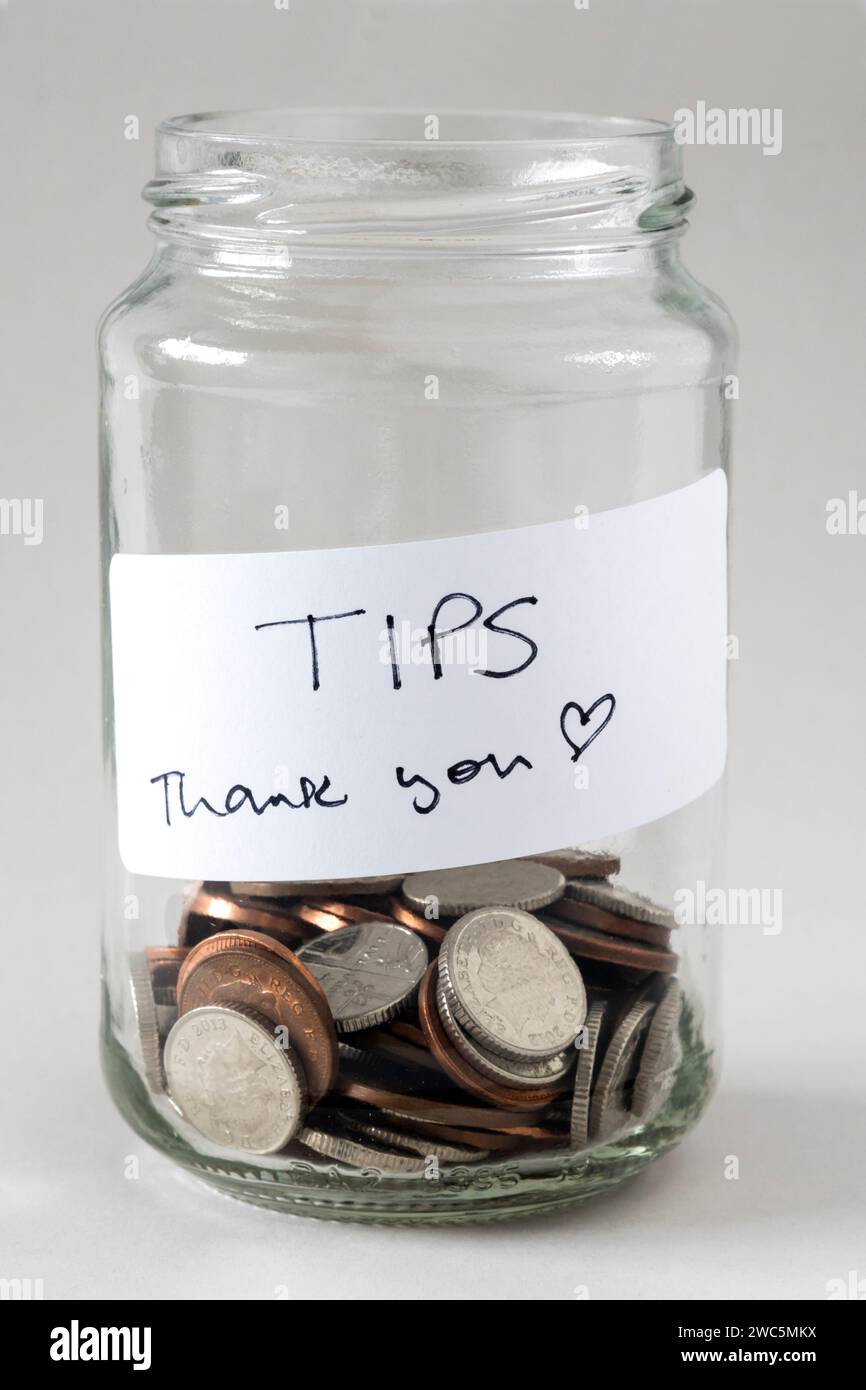 Ein Trinkgeldglas mit Geld und einem Etikett mit der Aufschrift „Tipps und Danke“. Stockfoto