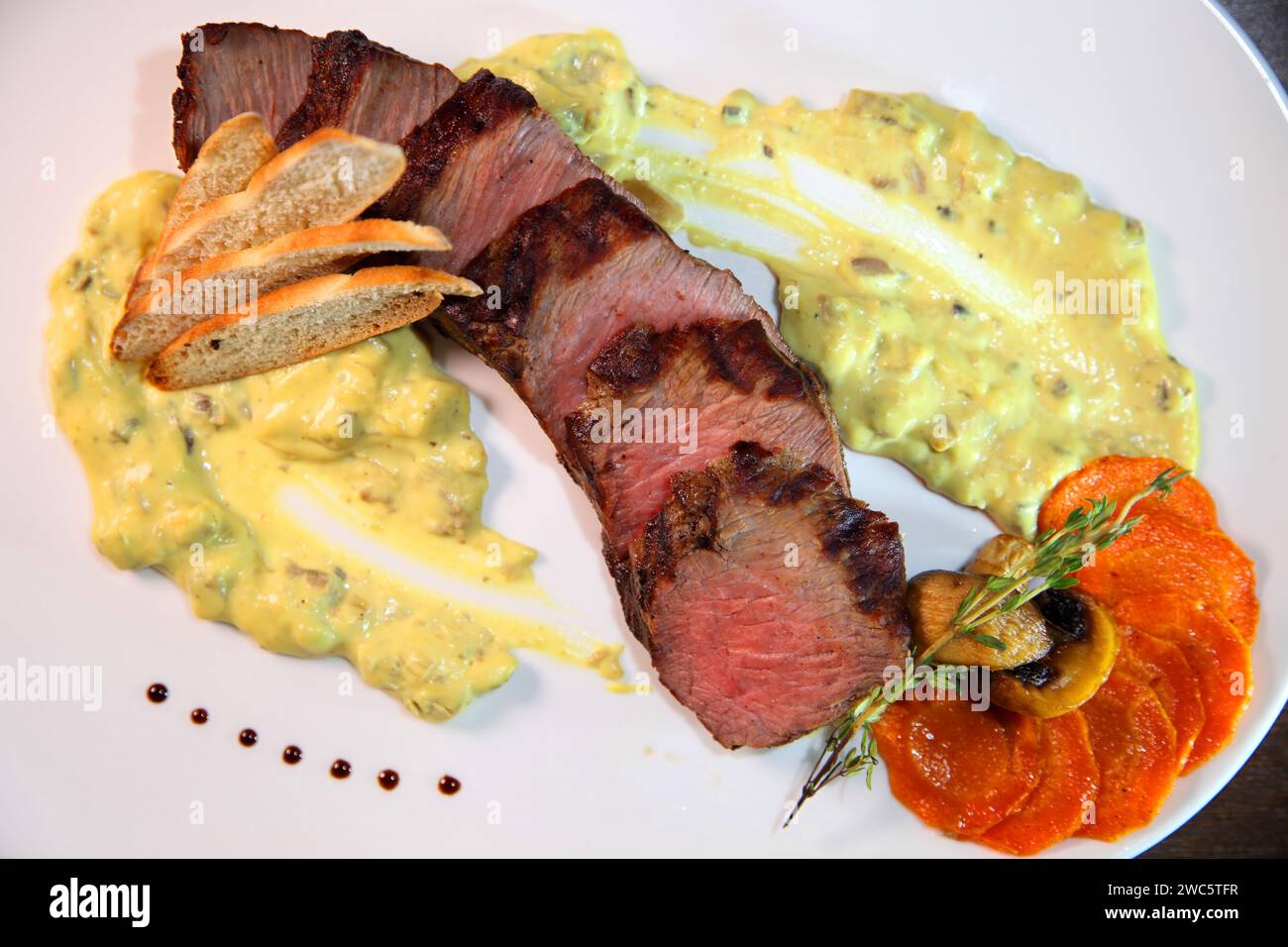 Mittelgroßer Braten, in Stücke geschnitten in cremiger Pilzsauce. Steak wird auf einem weißen Teller und Holztisch serviert. Stockfoto