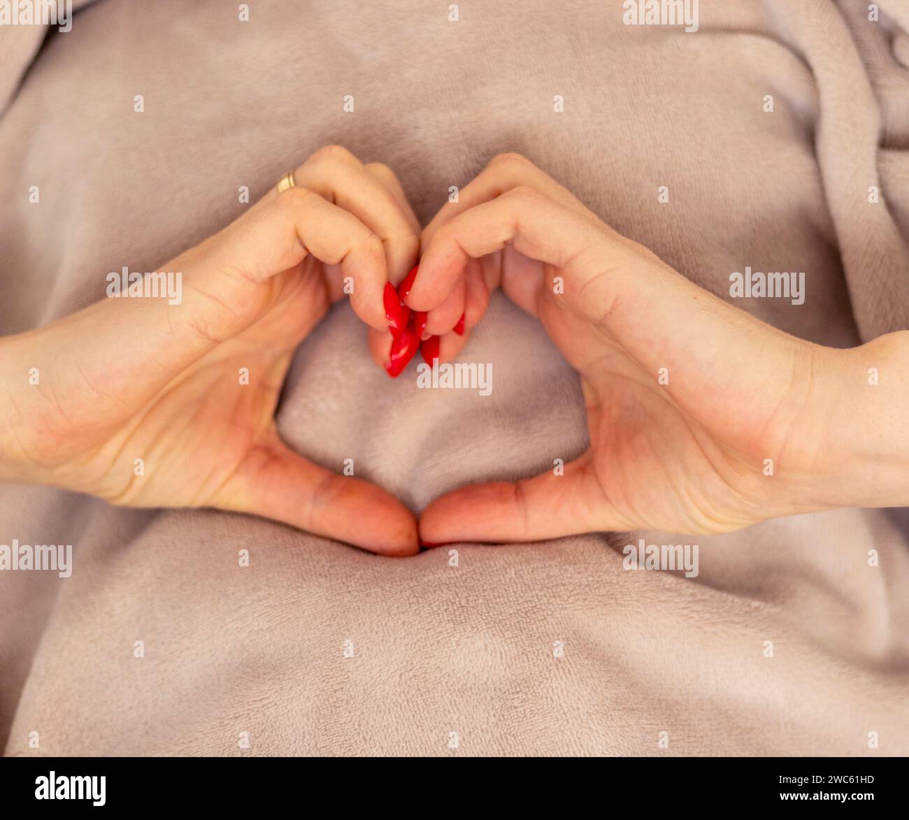 Die Frau hält ihre Hände in Form des Herzens als Symbol der Liebe Stockfoto