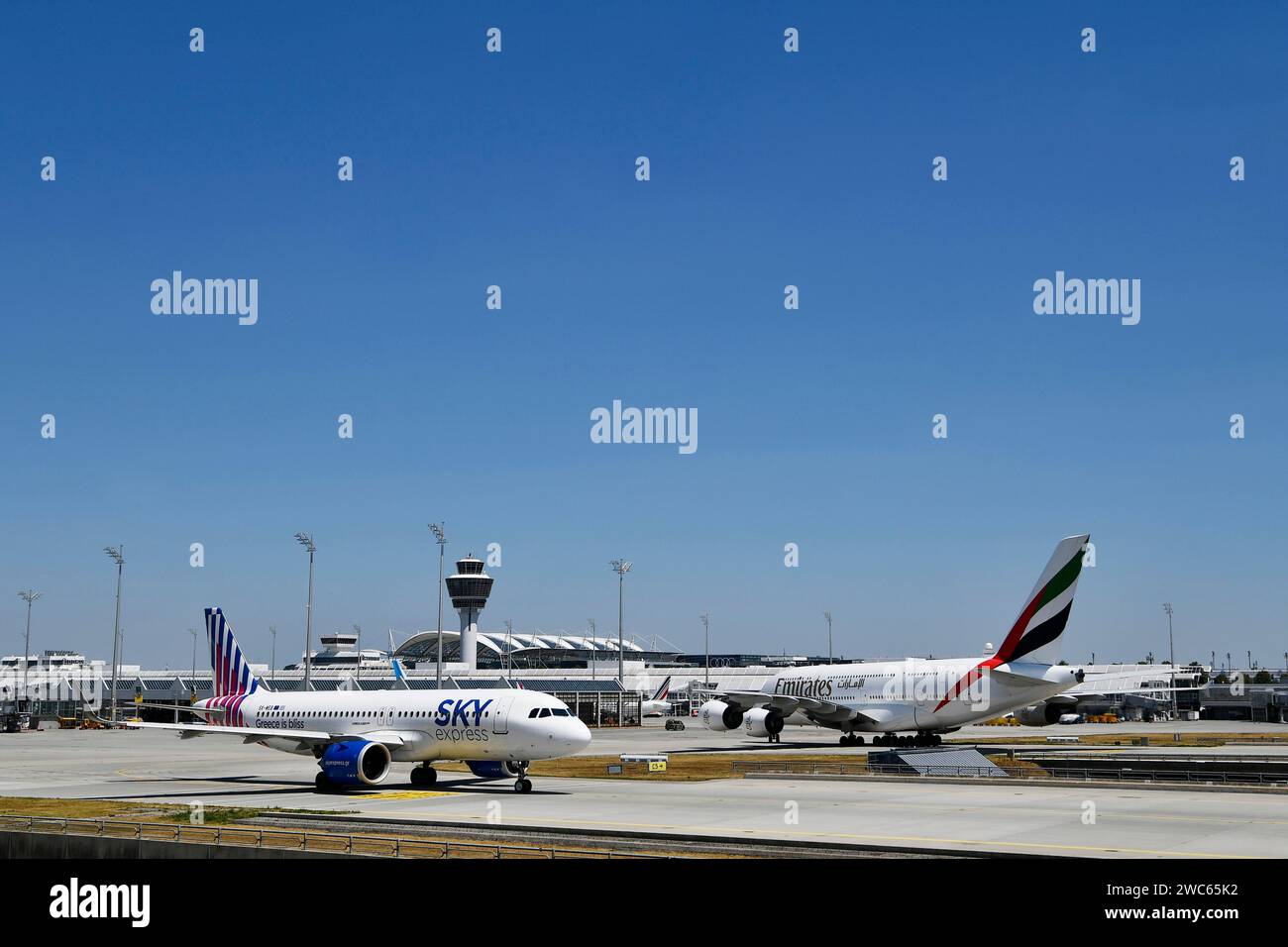Sky Express Airbus A320 Neo und Emirates Airbus A380-800 auf dem Vorfeld vor Terminal 1 mit Turm, Flughafen München, Oberbayern Stockfoto