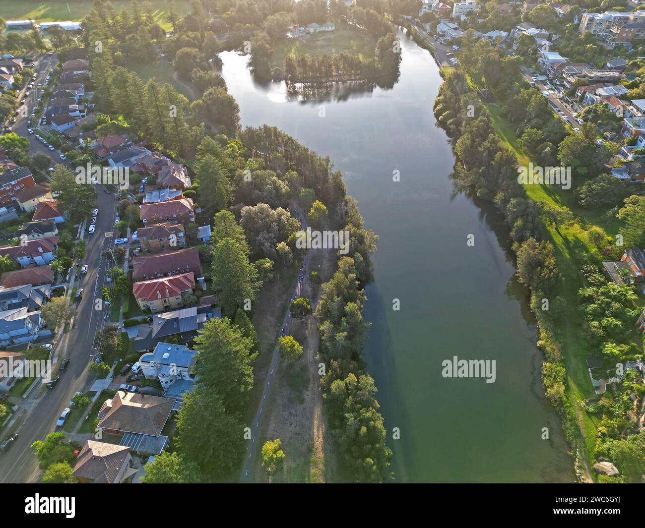 Ein ruhiger Fluss schlängelt sich durch eine malerische Landschaft mit charmanten Häusern in der Ferne Stockfoto