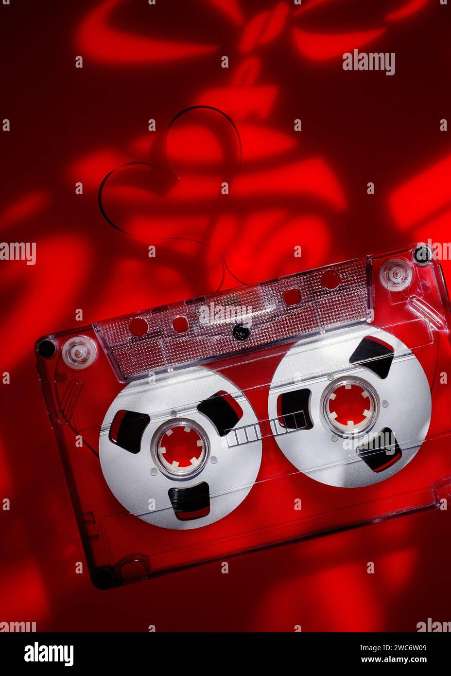 Lichtprojektionen zu einem festlichen Weihnachtsthema auf rotem Acryl mit Audiokassette. Vertikales Foto. Stockfoto