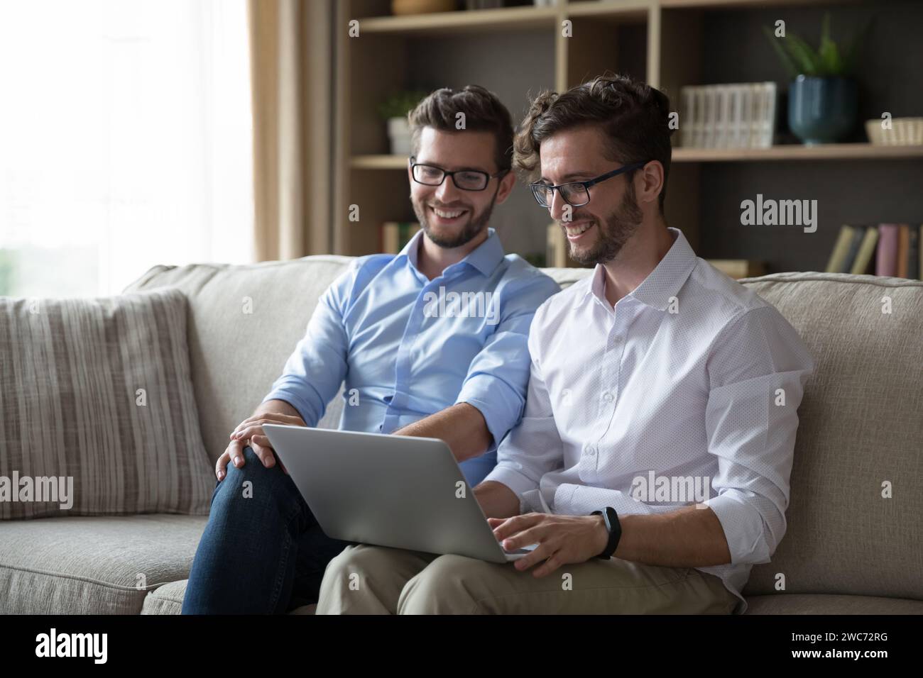 Zwei erwachsene Brüder entspannen sich zu Hause mit Laptop Stockfoto