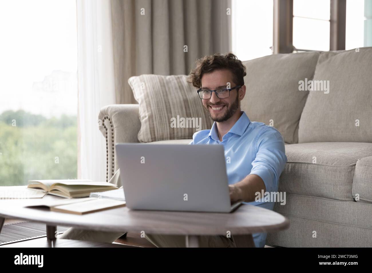 Mann sitzt am Tisch mit Laptop, lernt, schaut Lehrvideos an Stockfoto