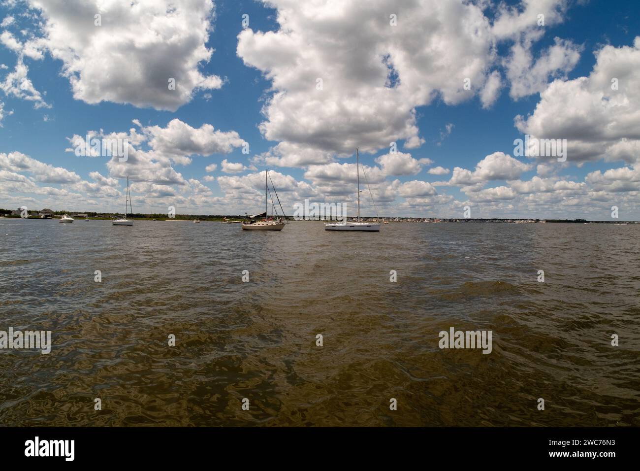 Dieses atemberaubende Foto zeigt die ruhige Schönheit eines Sees mit drei Booten, die anmutig über das glitzernde Wasser gleiten Stockfoto