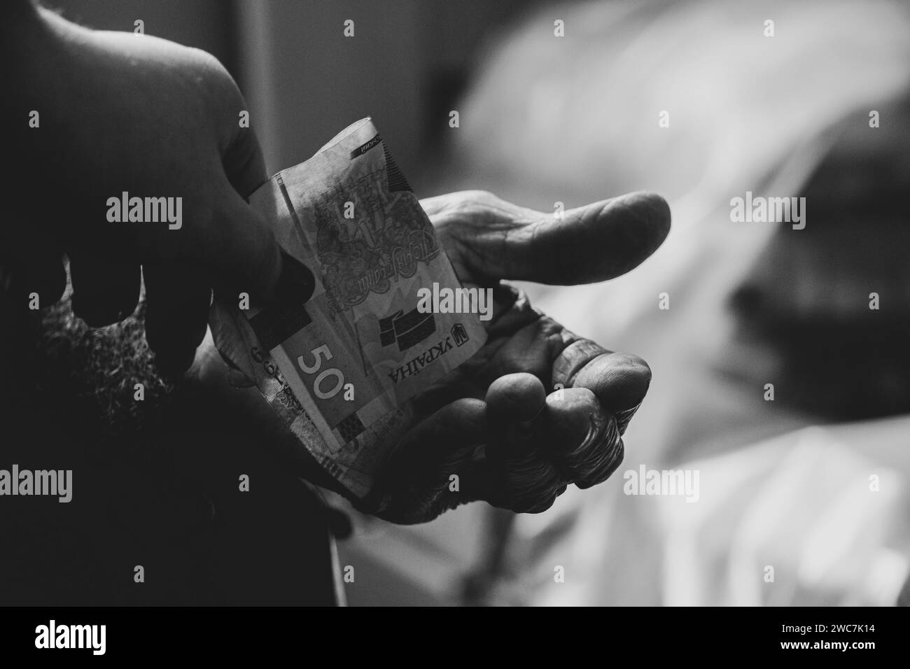 Die Hand einer Frau gibt ihrer Großmutter 50 Griwna, bittet und gibt Geld, finanzielle Unterstützung für alte Menschen, Hilfe Stockfoto