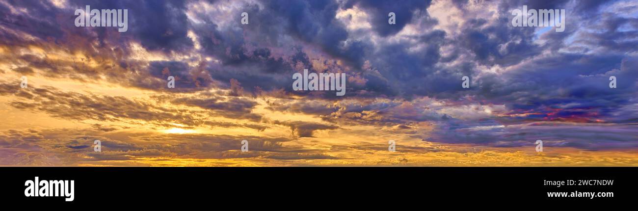 Der Himmel nach einem Sturm. Reich an wirbelnden Wolken und Flecken aus Blau, tiefem Violett, feurigen Orangen und sanften Gelbtönen. Stockfoto