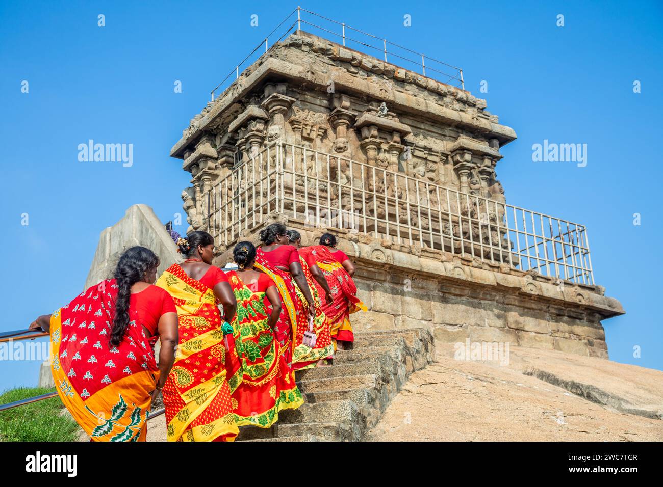 Gruppe von Pilgerfrauen in farbenfrohen roten und gelben Sarees auf dem Weg zum Olakkannesvara Tempel, Mahabalipuram, Tondaimandalam Region, Tamil Nadu Stockfoto