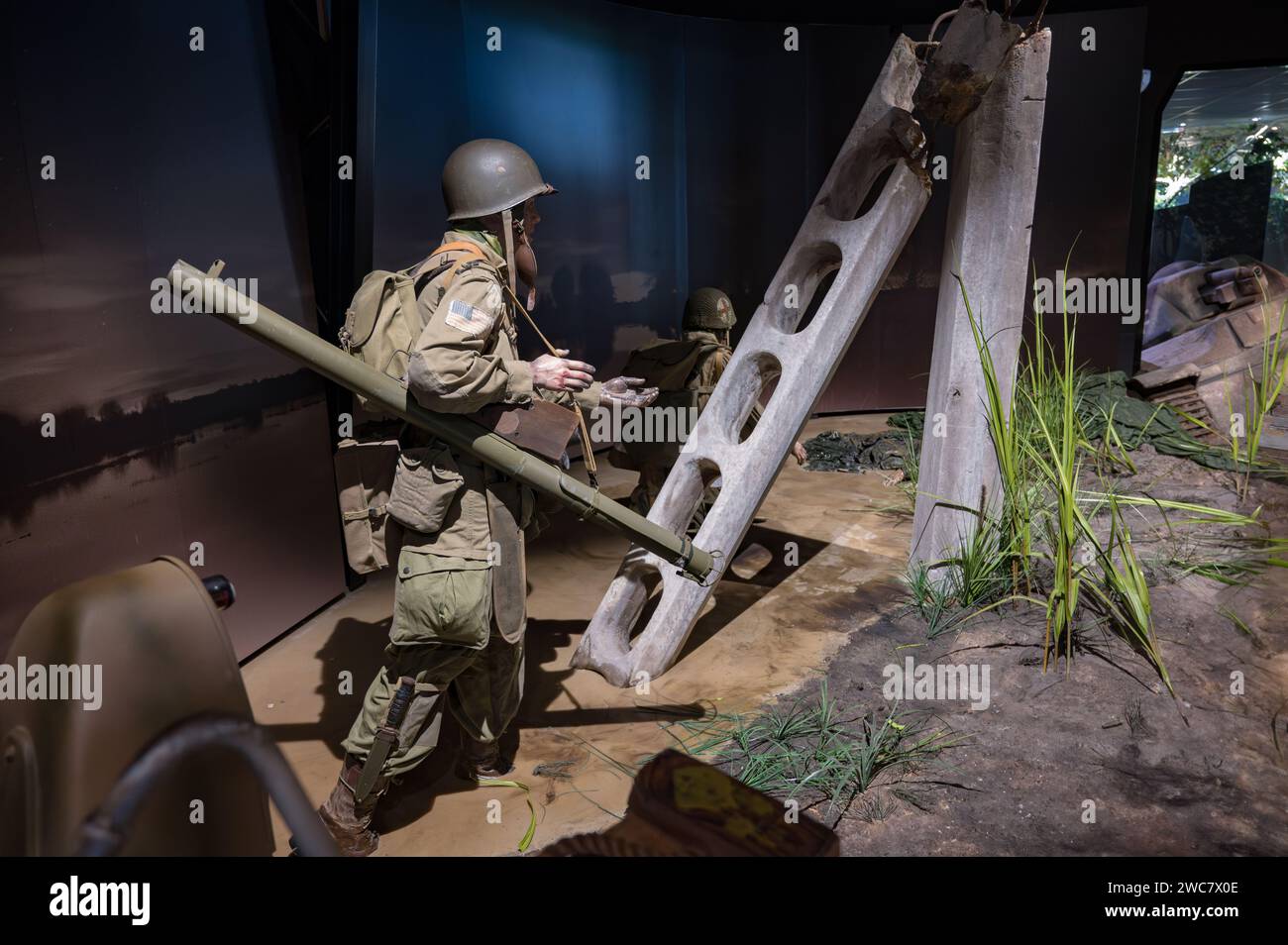 Detail eines amerikanischen Luftsoldaten, der nachts einen Raketenwerfer vom Typ Bazooka in den Ruinen der Straßen Frankreichs trägt Stockfoto