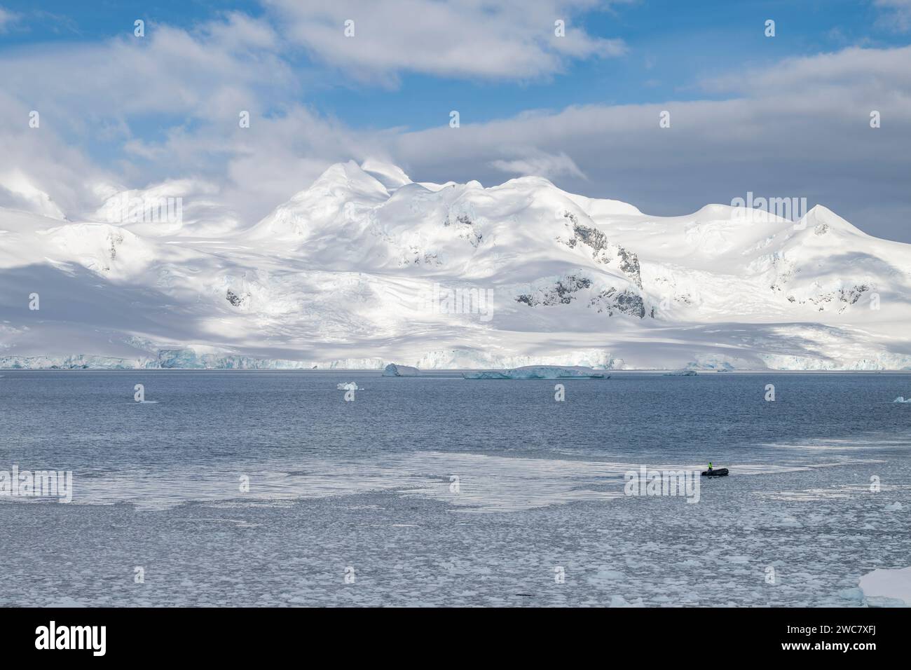 Zodiac navigiert durch das eisgefüllte Wasser von Neko, Hafen, Antarktis, aus nächster Nähe auf geerdete Eisberge, die sich auf dem umliegenden Wasser spiegeln Stockfoto