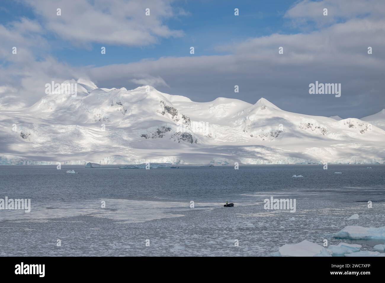 Zodiac navigiert durch das eisgefüllte Wasser von Neko, Hafen, Antarktis, aus nächster Nähe auf geerdete Eisberge, die sich auf dem umliegenden Wasser spiegeln Stockfoto