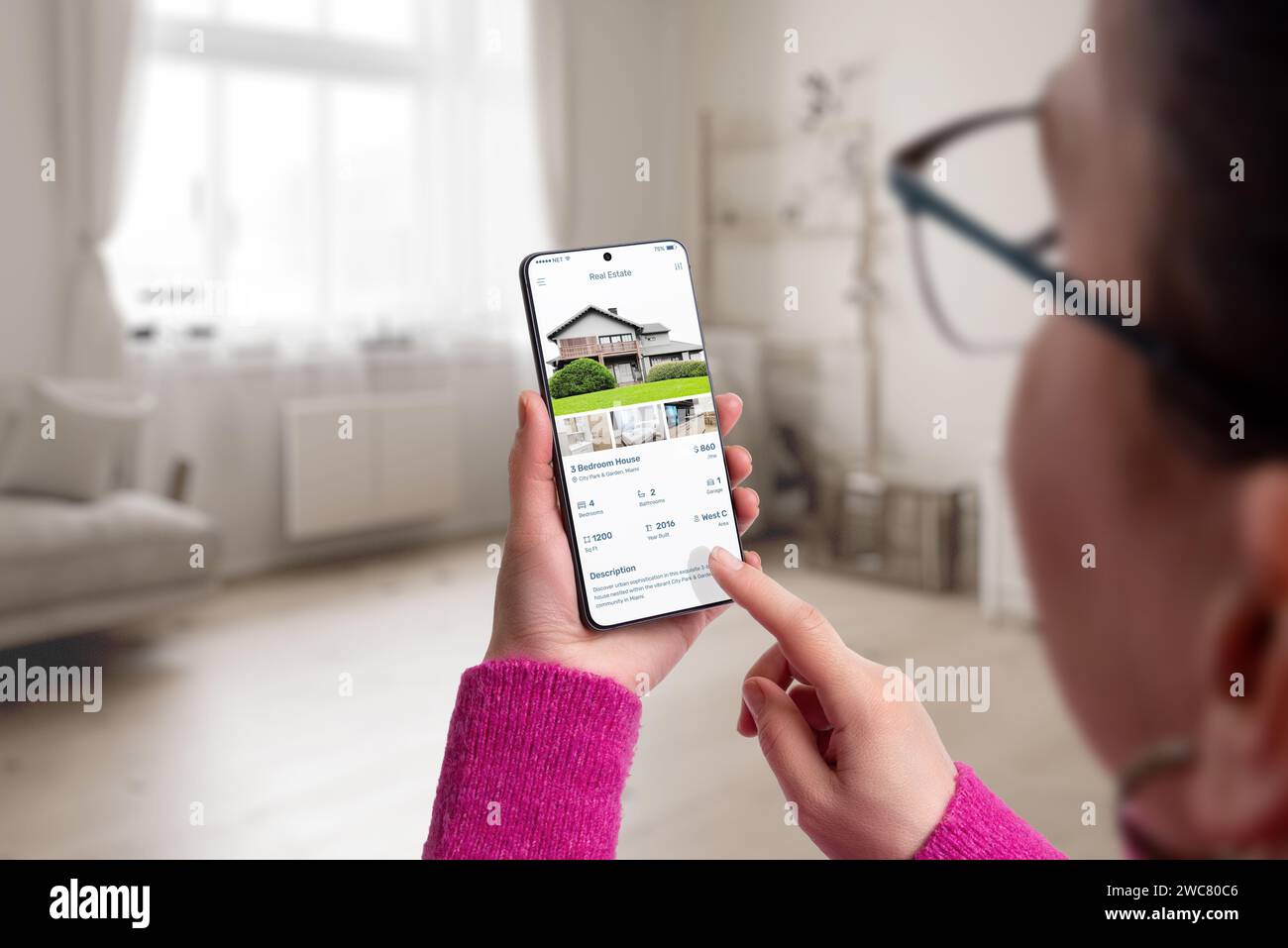 Smartphone mit einer App für Wohnimmobilien in Frauenhänden. Wohnzimmereinrichtung im Hintergrund, die moderne Technologie mit Zuhause verbindet Stockfoto